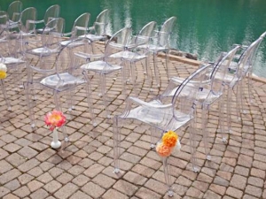 Clear ghost chairs with arms at the pool